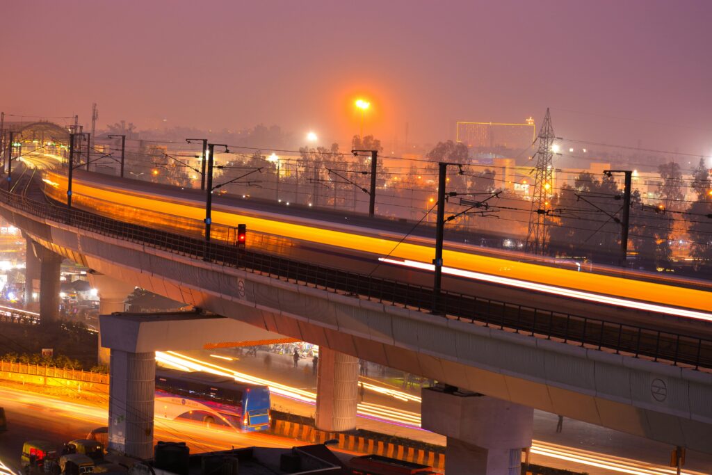 Dynamic night view of a modern city with illuminated train tracks showcasing speed and urban life.